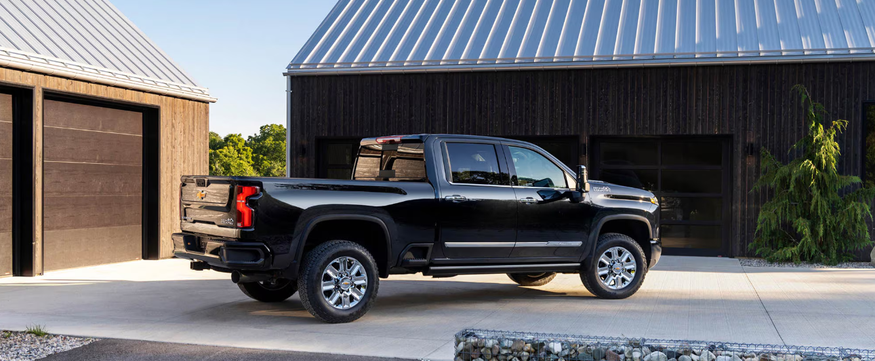Black Chevrolet Silverado HD parked beside a dark barn-style garage