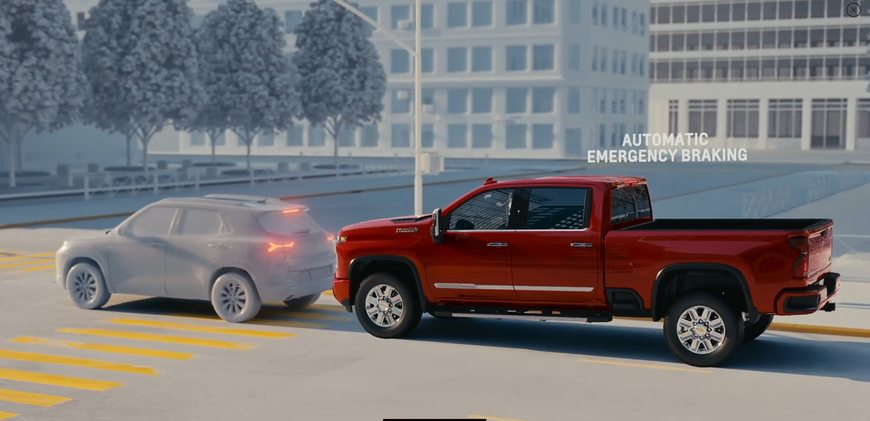 Red Chevrolet Silverado HD braking behind an SUV with an Automatic Emergency Braking alert