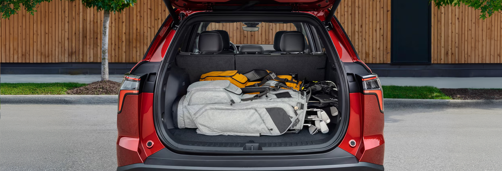 Red Chevrolet Equinox with its liftgate open showing bags packed in the cargo area
