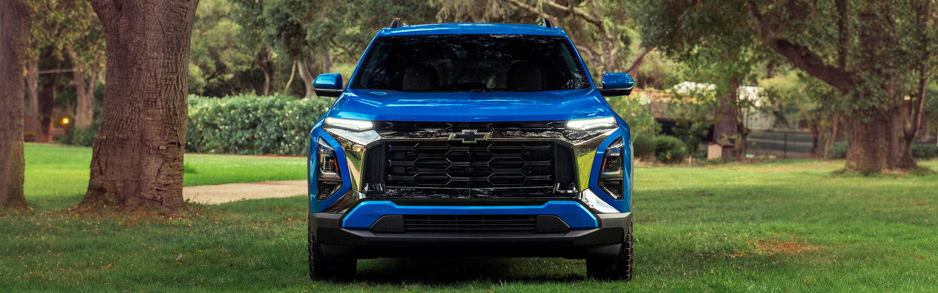 Blue 2027 Chevrolet Equinox ACTIV parked head-on in a grassy park
