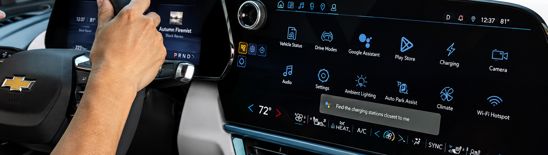 Driver's hand on the gear selector beside the Chevrolet center touchscreen showing Google built-in apps