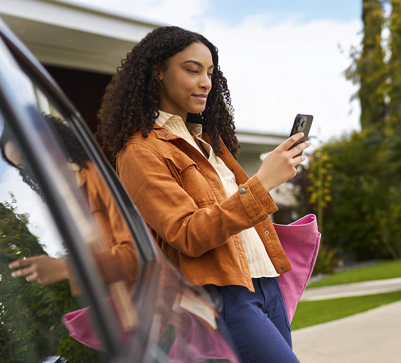 Woman checking her phone as she steps out of a Chevrolet