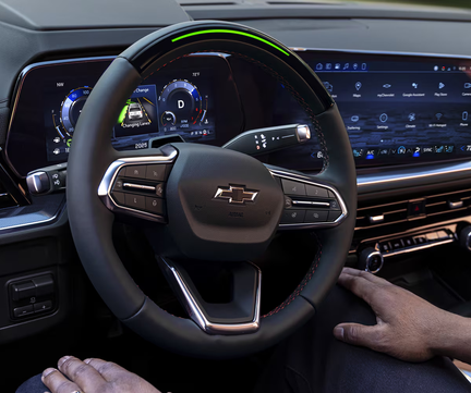 Driver's hands off the Chevrolet Tahoe steering wheel with the Super Cruise light bar glowing green