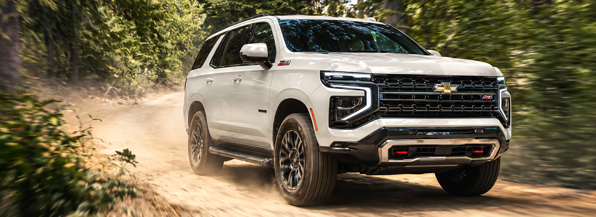 White 2027 Chevrolet Tahoe Z71 kicking up dust on a wooded dirt trail