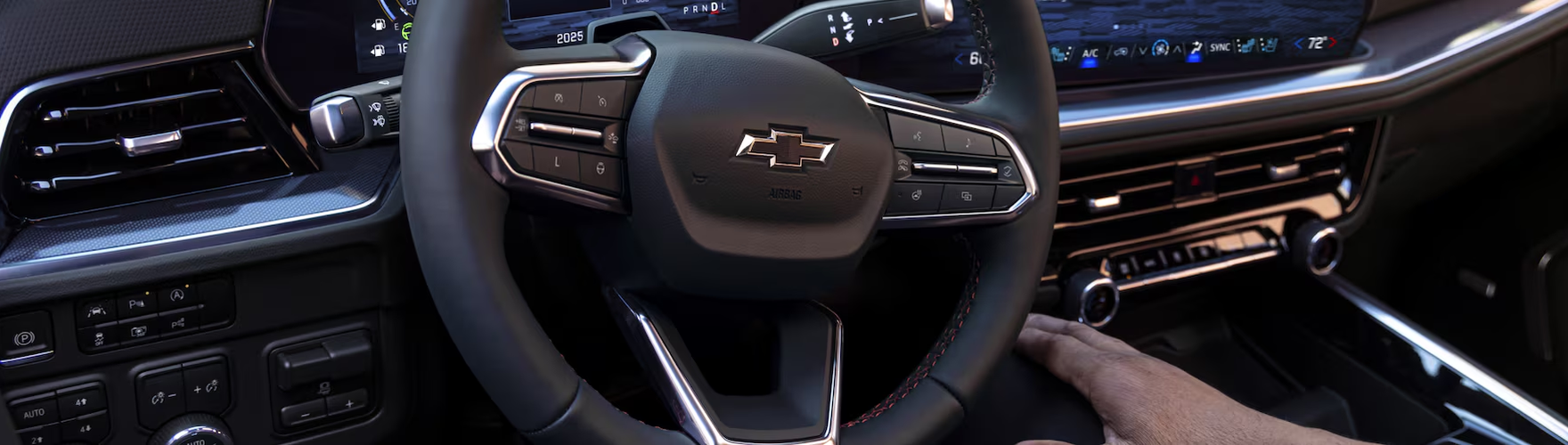 Driver's hand on the Chevrolet Tahoe steering wheel below the digital driver display