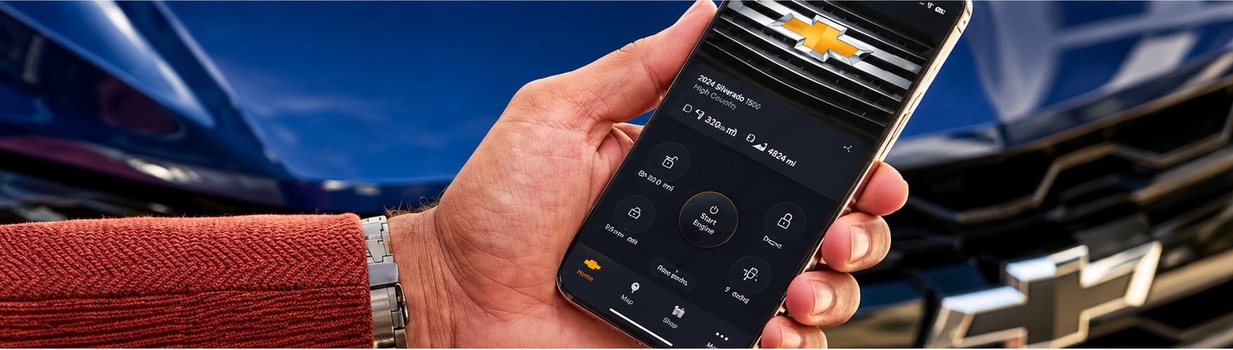 Hand holding a phone with the Chevrolet app open beside a Chevrolet bowtie