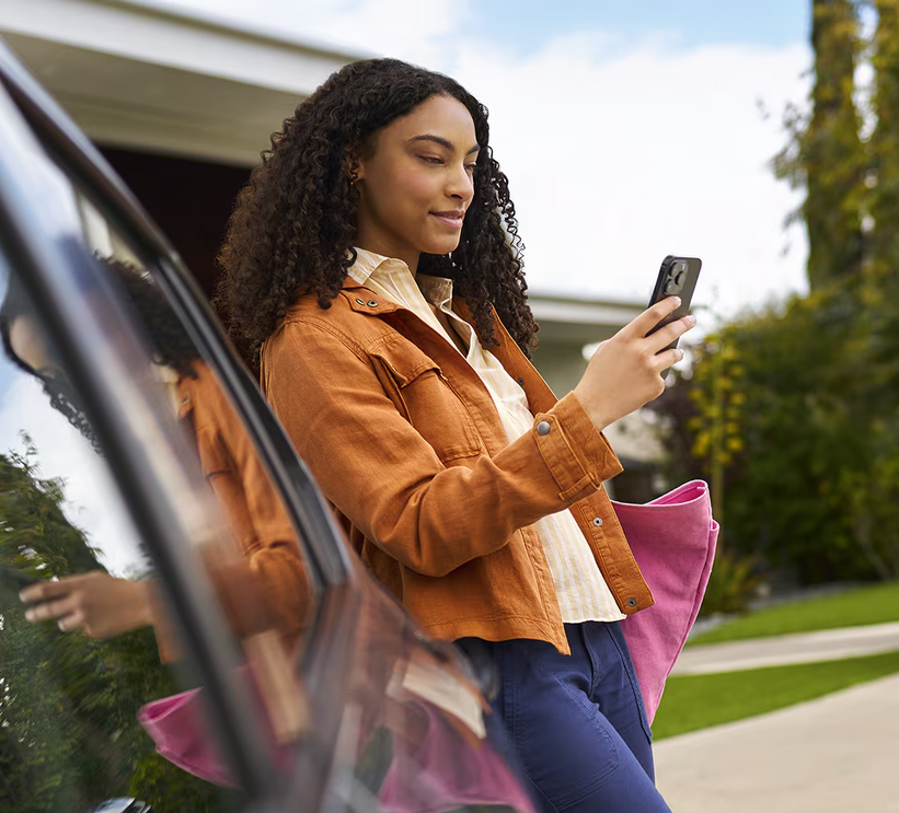 Woman checking her phone as she steps out of a Chevrolet