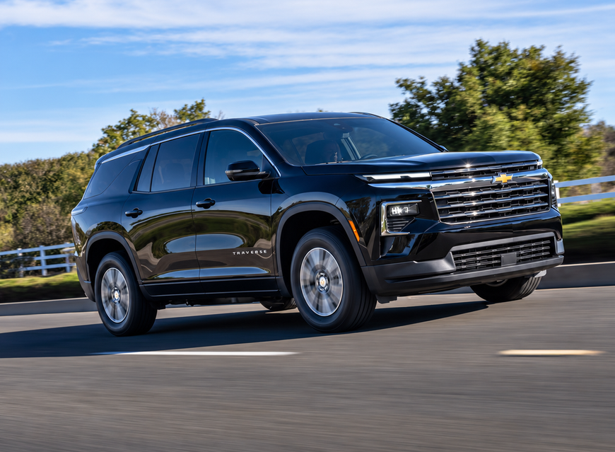 Black Chevrolet Traverse LT driving on a tree-lined road