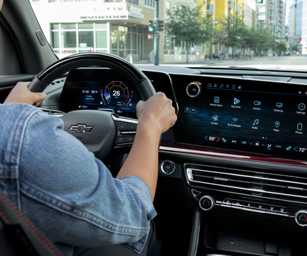 Driver's hands on the Chevrolet Traverse steering wheel beside the center touchscreen