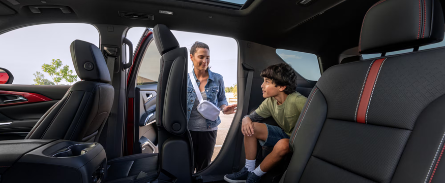 Mother and son at the open rear door of a Chevrolet Traverse with black and red seats