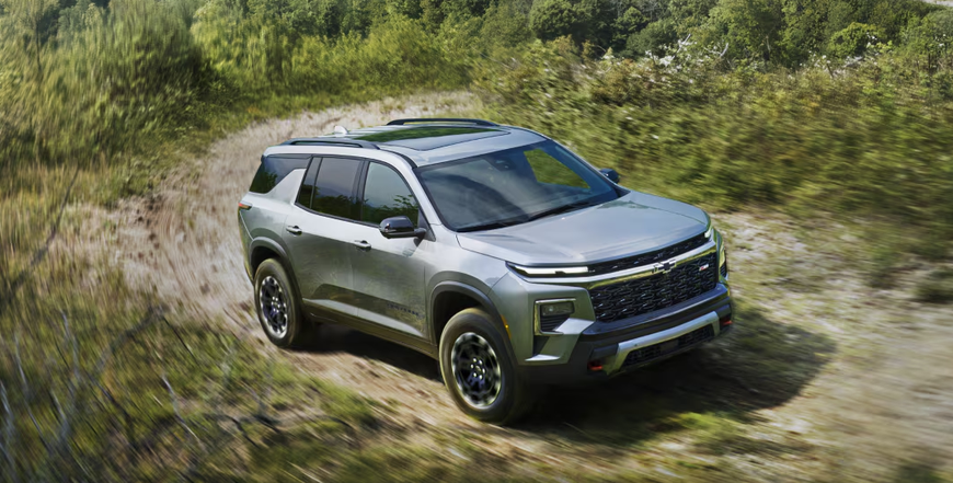 Silver Chevrolet Traverse Z71 driving along a dirt trail through tall grass
