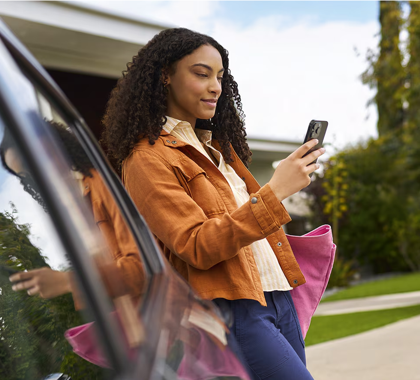 Woman checking her phone as she steps out of a Chevrolet