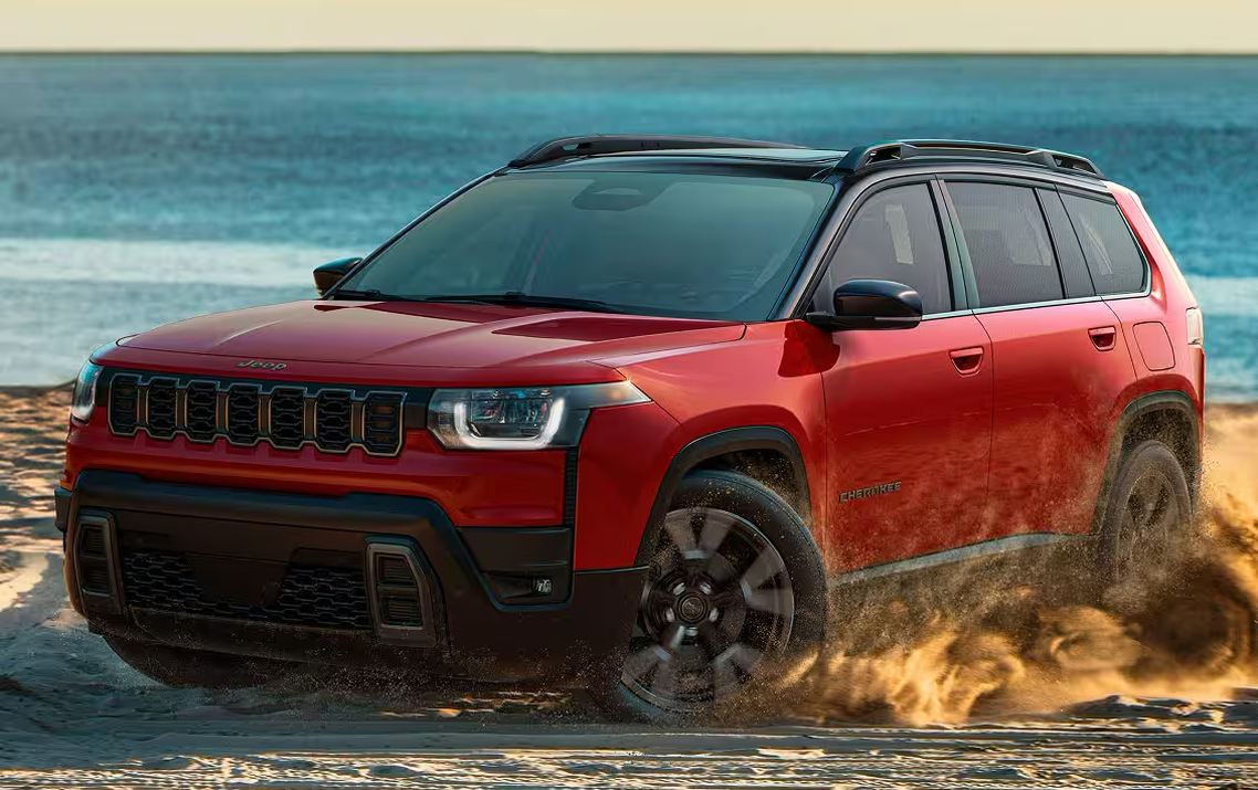 Red 2027 Jeep Cherokee driving through beach sand