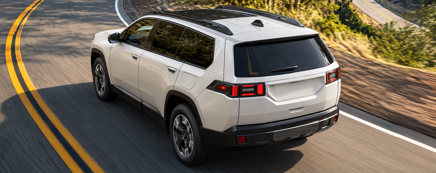 White 2027 Jeep Cherokee driving on a winding two-lane road