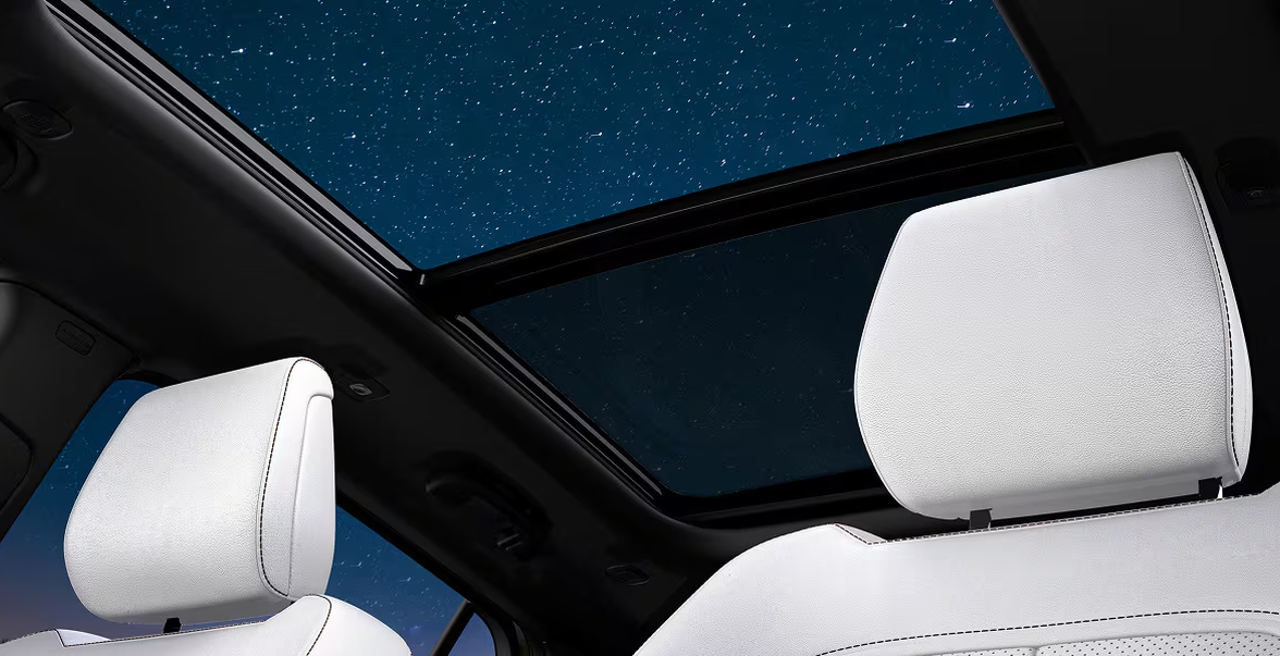 Night sky seen through the Dual-Pane Panoramic Sunroof above white leather seats