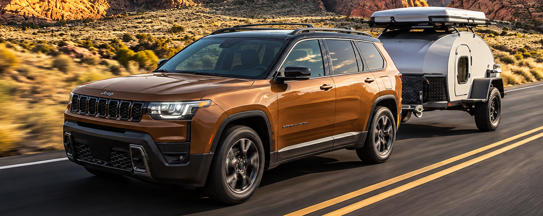 Copper 2027 Jeep Cherokee towing a teardrop camper trailer on a desert highway