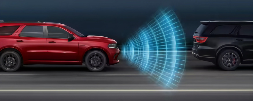 Red Dodge Durango keeping a safe distance behind a black vehicle with radar graphics