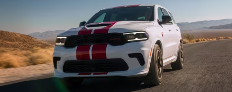 White Dodge Durango with red racing stripes driving on a desert highway