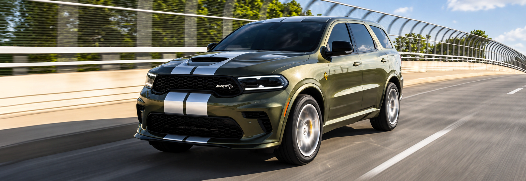 Olive green Dodge Durango SRT with silver racing stripes driving across a bridge