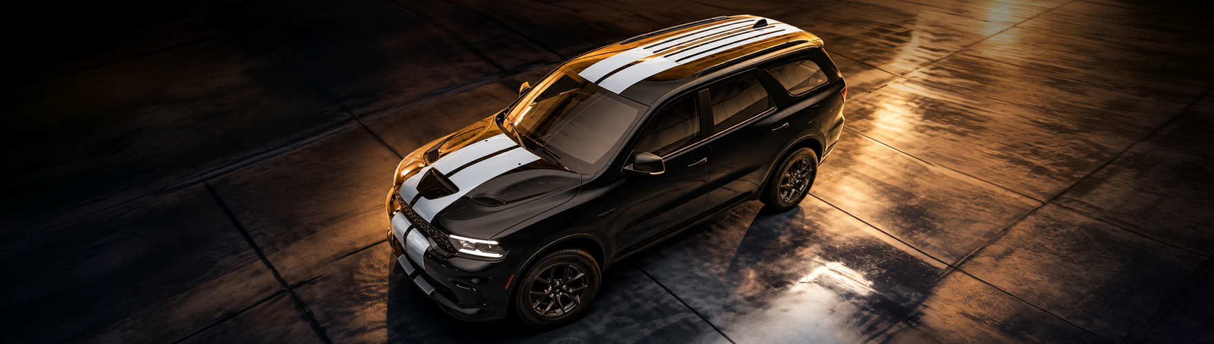 Overhead view of a black Dodge Durango with white racing stripes on wet pavement at night