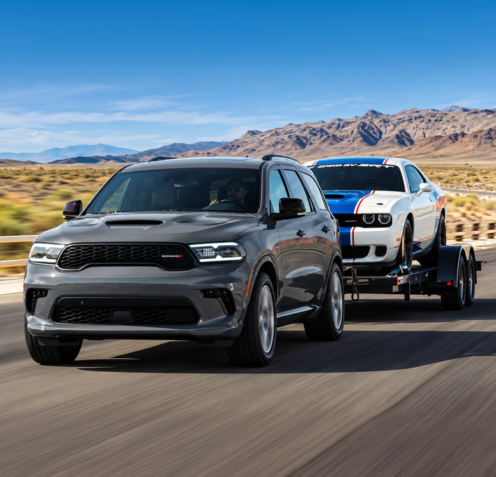 Gray Dodge Durango towing a white car on a trailer through the desert