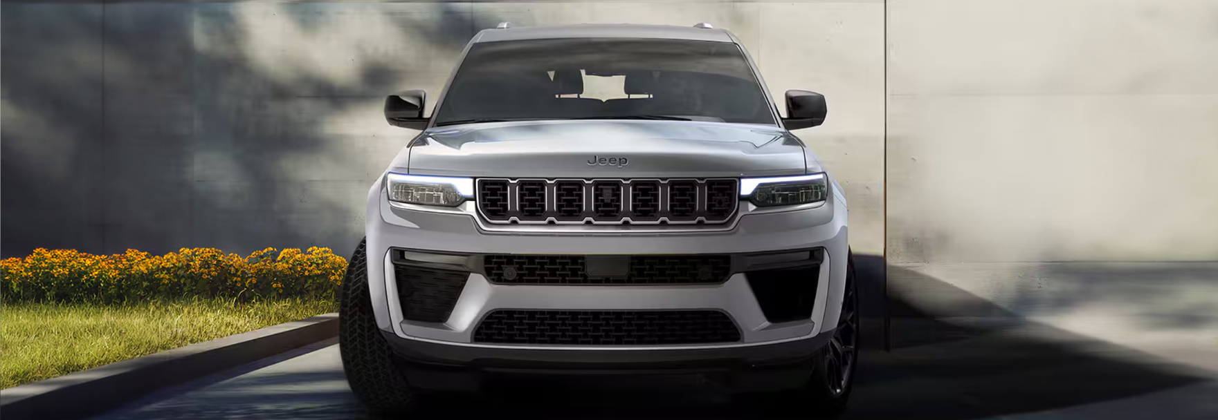 Front view of a silver Grand Cherokee in front of a concrete wall