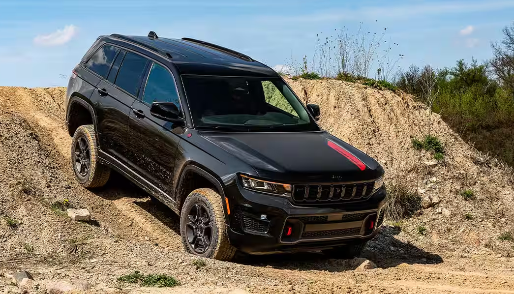 Black Grand Cherokee Trailhawk descending a steep dirt mound