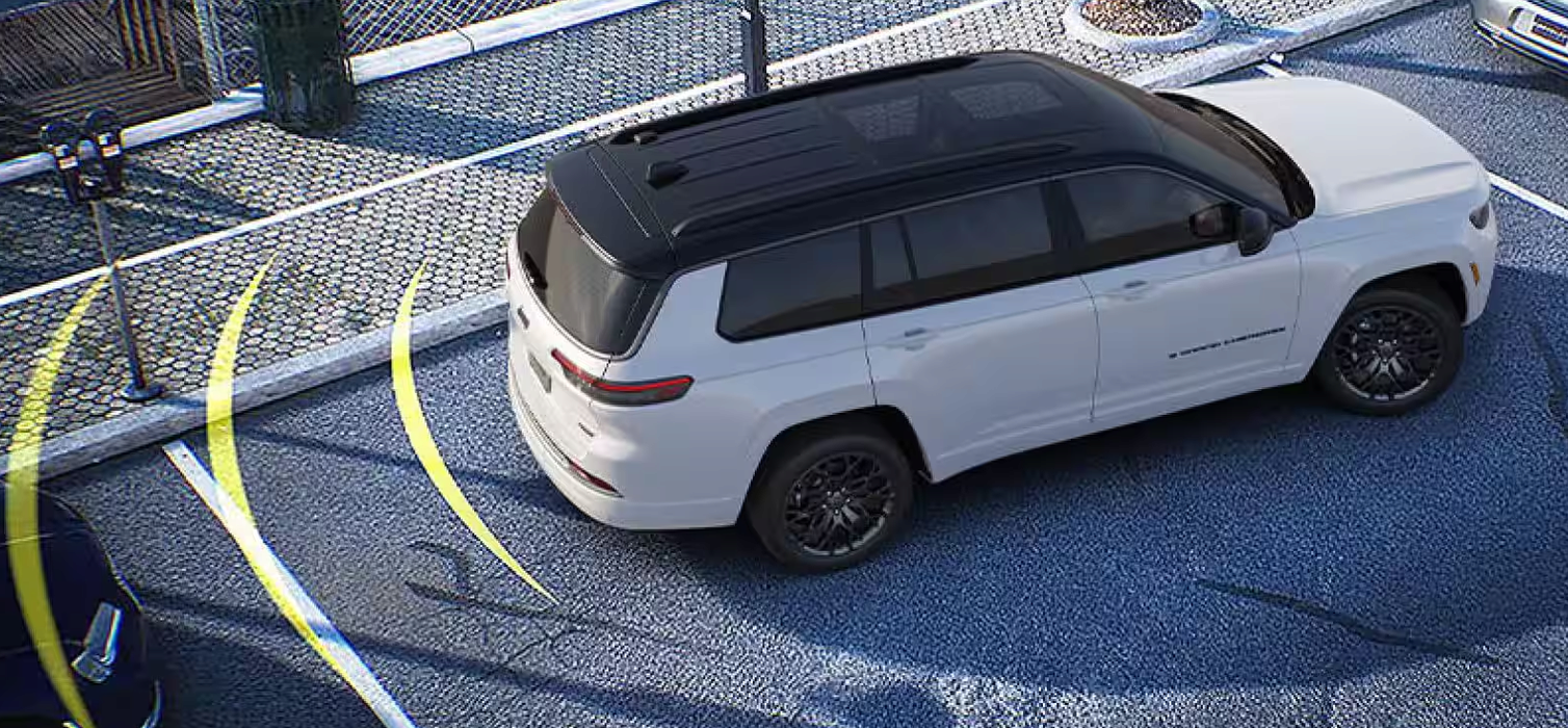 White Grand Cherokee L backing into a parking space with sensor arcs shown