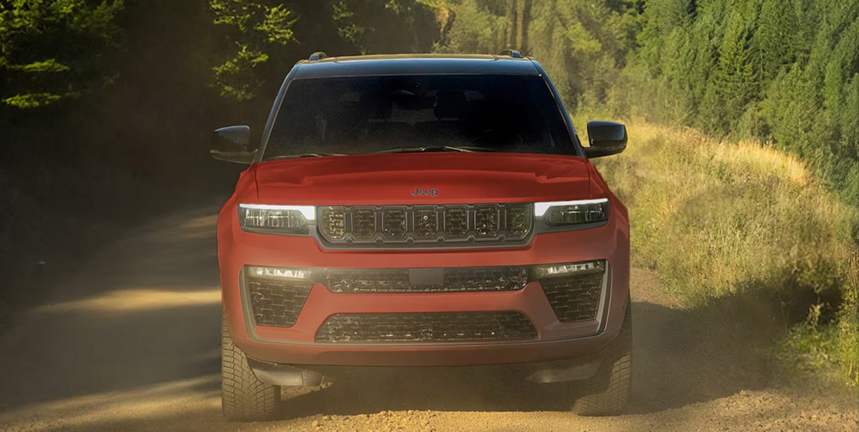 Red Grand Cherokee driving down a forest dirt road