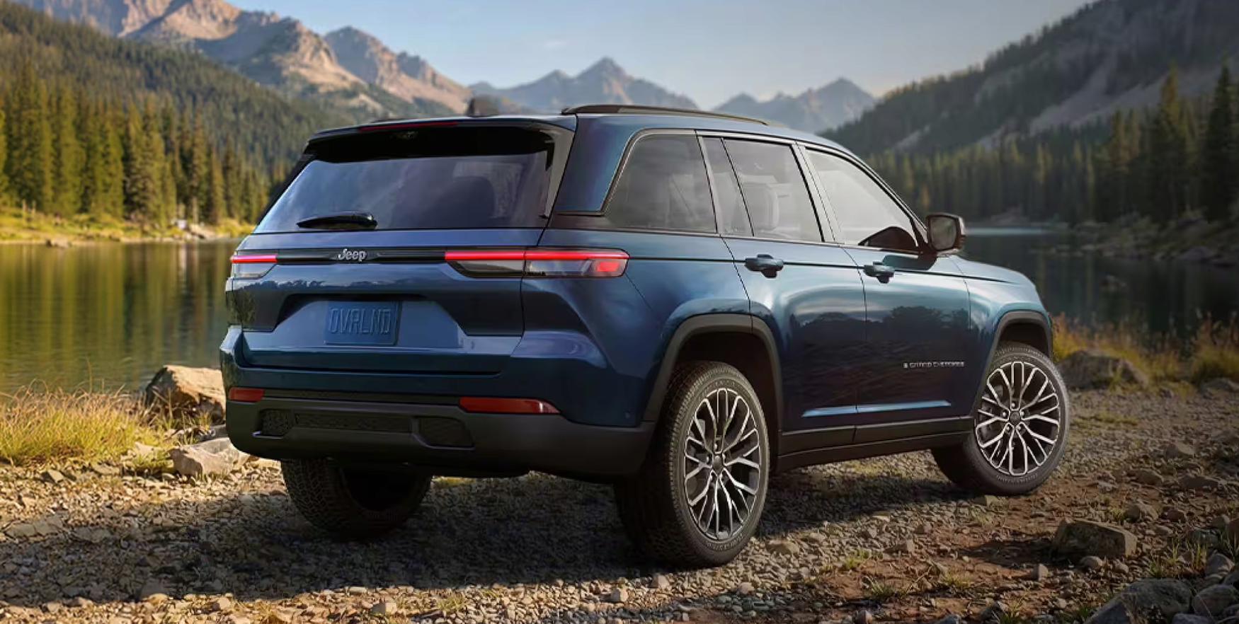 Rear view of a blue Grand Cherokee parked by a mountain lake