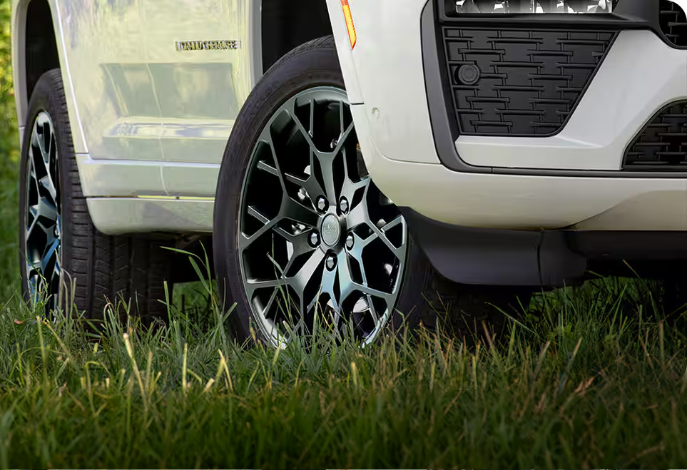 Front wheel of a white Grand Cherokee raised on grass