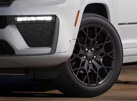 Front corner of a white Grand Cherokee with a gloss black wheel