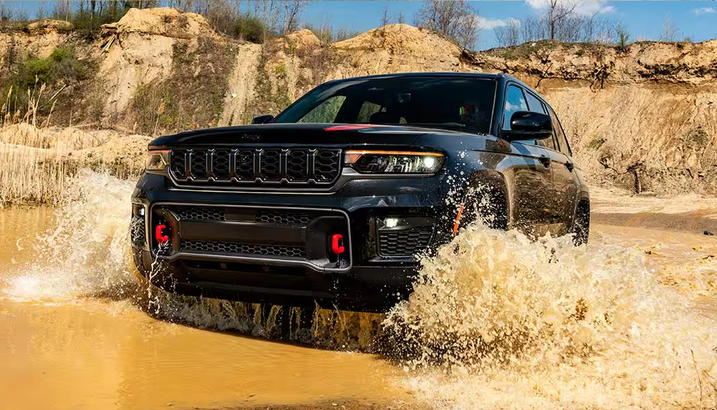 Black Grand Cherokee Trailhawk splashing through a muddy pond