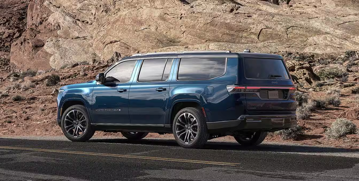 Blue 2027 Jeep Grand Wagoneer in profile in front of rock formations