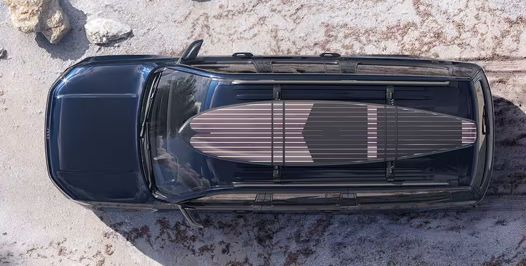 Overhead view of a dark 2027 Jeep Grand Wagoneer carrying a surfboard on its roof