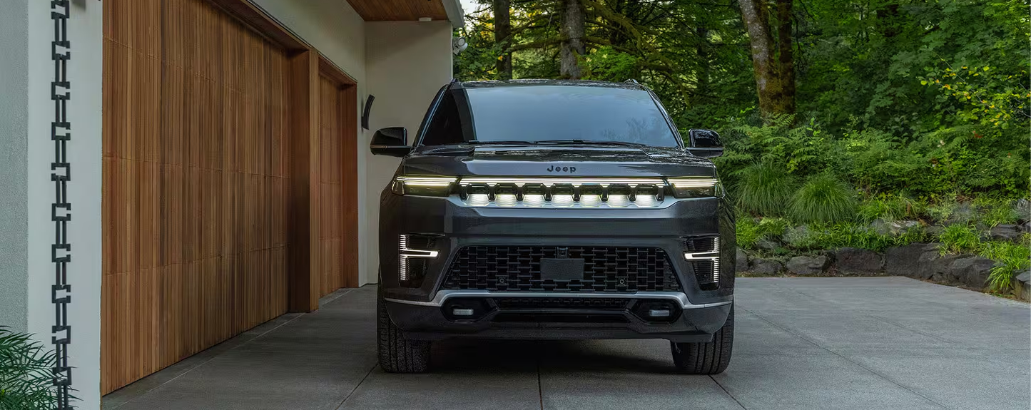 Front of a dark 2027 Jeep Grand Wagoneer with its illuminated seven-slot grille