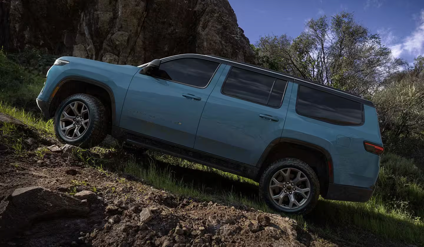Light blue 2027 Jeep Grand Wagoneer climbing a steep dirt slope